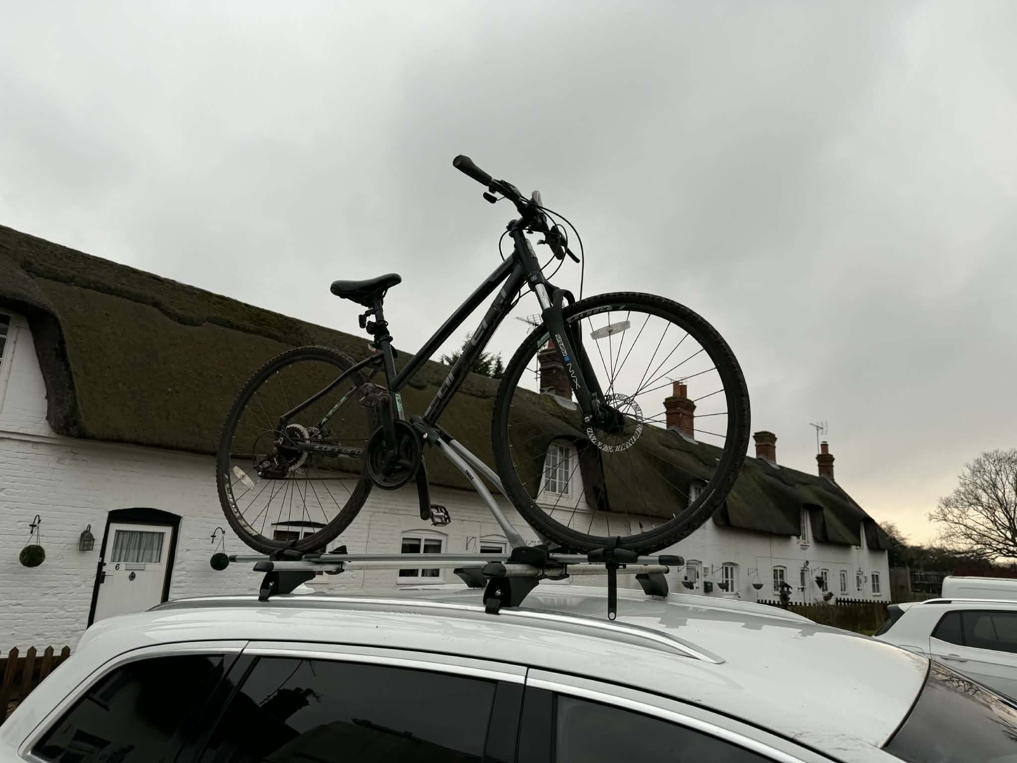 black road bike parked beside brown wooden wall